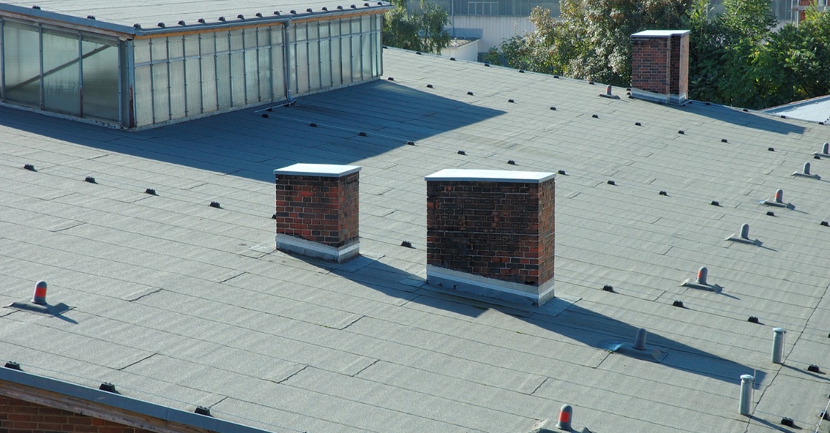 Flat commercial roof with multiple penetrations, vents, and brick structures