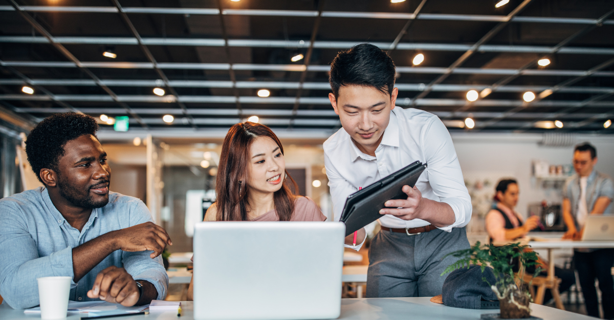 Three professionals discussing energy efficiency strategies around a laptop in a modern office